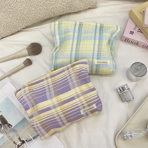 Close-up of colorful checkered fabric makeup bags with zipper and brand label details