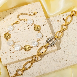 Fashionable gold chunky oval link bracelets with pearls and coin charms on silk background