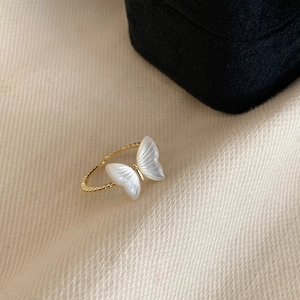 Detailed macro view of golden butterfly ring with white shell texture on textured fabric