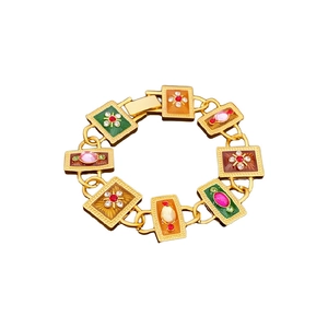 Vintage gold link bracelet with colorful enamel floral accents on a white background