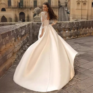 Elegant ivory satin wedding dress with lace embroidery and long train in sunlight