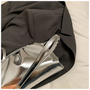 Detail of silver metallic pleated cloud bag resting on a stylish dark grey blazer suit