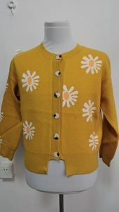 Detail of yellow knit cardigan featuring white daisy embroidery and marble-pattern buttons