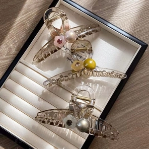 Three elegant jelly flower pearl hair claws in pink, yellow, and white on a jewelry tray