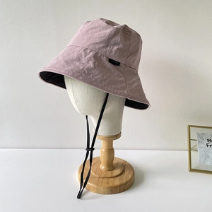 Detail of pink nylon bucket hat with adjustable windproof rope and side label