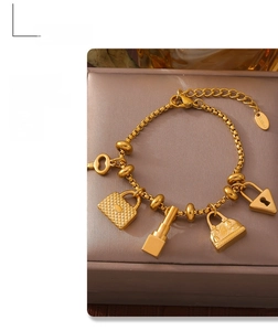 Detail of gold titanium steel bracelet with chic handbag and lipstick charms
