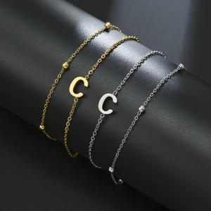 Detail shot of the gold and silver alphabet C letter charm on a beaded metal chain