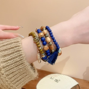 Detail of layered bohemian sandalwood bracelet with blue beads, gold accents and tassel