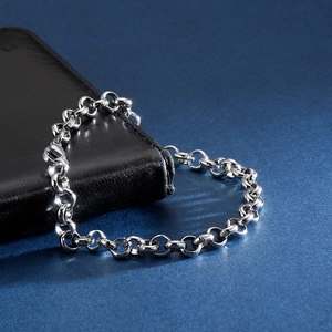 Close-up of a silver stainless steel rolo chain bracelet with lobster clasp on leather