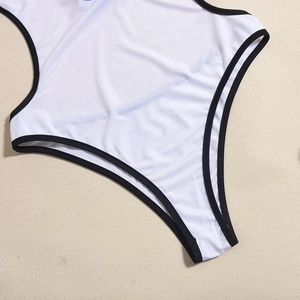 Detailed view of white one-piece swimsuit with black trim edges and elastic fabric texture