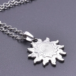 Detailed macro view of silver sun totem pendant with engraved spiral texture on chain