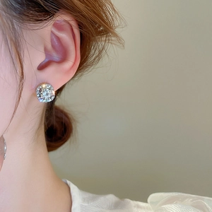 Close-up of sparkling cubic zirconia square stud earrings worn on a model's ear