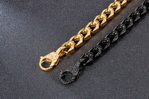 Macro shot of gold and black heavy link chains featuring textured lobster clasp closure