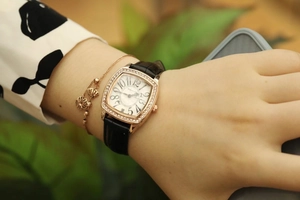 Close-up of square tonneau watch for women with rose gold diamond bezel and leather strap