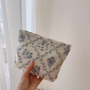 Detail of a floral cotton makeup bag with blue Toile de Jouy pattern and simple wish label