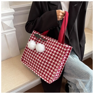 Detail of red houndstooth tote bag featuring a cute plush cherry charm and canvas texture