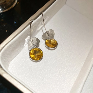 Detail of silver drop earrings with yellow round gemstones and polished metal sequins