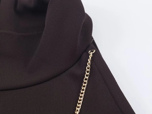 Detail of knit fabric texture with gold chain link trim on a halter neck dress