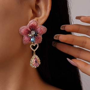 Gros plan d'une boucle d'oreille fleur brodée rose avec cristal sur l'oreille