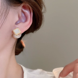 Close-up of elegant square zircon earrings with white pearl drop on a female model