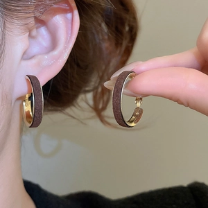 Detail view of round velvet earrings in dark brown with gold inner metal finish