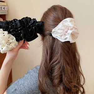 Vue détaillée de grandes pinces à cheveux en satin plissé avec fleurs et pois élégants