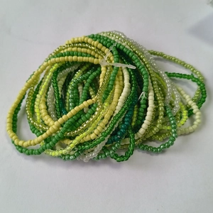 Detail of colorful stacked seed bead bracelets in green, yellow, and white tones
