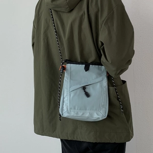 Detail of light blue nylon crossbody bag on a model showing size and fit for outdoors