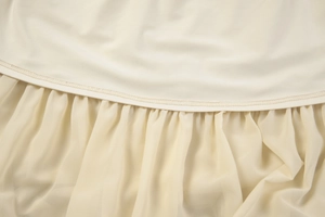Detailed view of beige chiffon ruffles and double-stitched hem on a French style top
