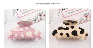 Détail de pinces à cheveux à motif vache rose et beige avec une finition en résine brillante