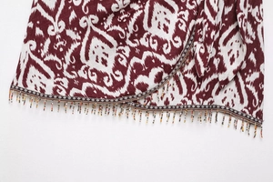 Detail eines Stoffes mit Ethno-Muster und bunten Perlenfransen am Saum für Damenmode