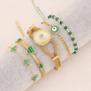 Ensemble de 4 bracelets dorés avec charms coeur vert et détail papillon sur un présentoir