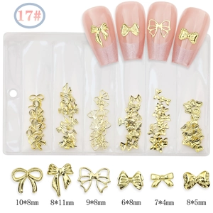 Detail view of 6 styles of gold alloy bow nail charms in a partitioned storage bag