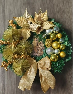 Detail of Christmas wreath with golden poinsettia, pine cones, and nativity scene design