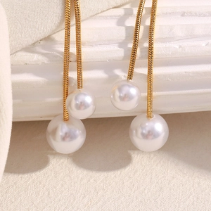 Detail of 18K gold plated tassels with elegant white pearls on geometric earrings
