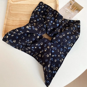 Detailed close-up of floral fabric scrunchie with yellow and blue flowers on black