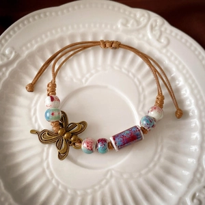 Close-up of ceramic beads and bronze butterfly charm on hand-woven rope bracelet