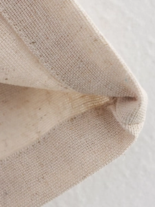 Macro shot of reinforced double stitching on beige linen vest hem and fabric texture