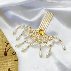 Detailaufnahme des goldenen Fächer-Haarkamms mit weißen Perlen und gelbem Edelstein