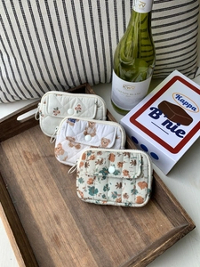 Quilted cotton pouches featuring berry, teddy bear, and floral patterns in a wooden tray