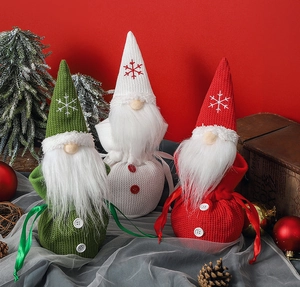 Close-up of three knitted Christmas gnome gift bags with snowflake embroidery and buttons
