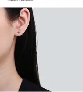 Macro shot of an 8-pointed star silver stud earring with a blue zircon on a woman's ear
