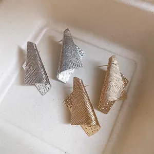 Irregular geometric metal stud earrings in gold and silver with textured finish