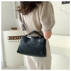 Chic black bucket bag with geometric quilted pattern worn by model in cafe setting