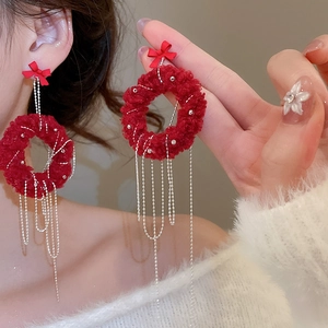 Detail of red plush wreath earring with festive bow and long silver tassel chain