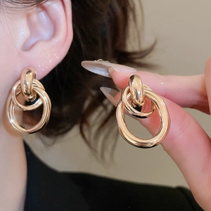 Detail of layered gold geometric circle earrings showing polished finish on model