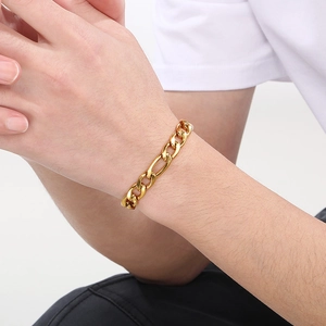 Detailed view of a gold-plated Figaro chain bracelet worn on a wrist for men and women