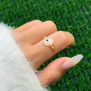 Detail of handmade gold wire-wrapped ring featuring a blue evil eye opal bead