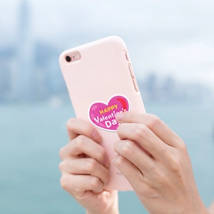 Close-up of pink heart Valentine's Day sticker on a phone case with scenic background