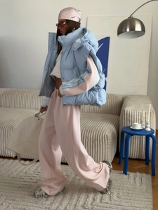 Detail of light blue quilted vest paired with pink jogger pants in a cozy indoor setting